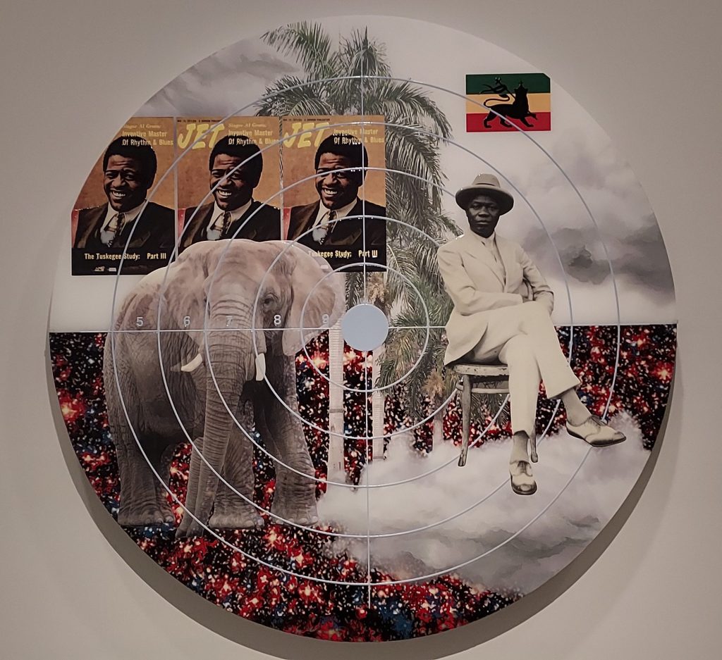 A circular, photo-based collage featuring an image of the Beninese Pan-Africanist Kojo Tovalou Houeriou (1887-1936), and symbols of African and diasporan cultural heritage, created by Bahamian artist Tavares Strachan. Gun crosshairs are superimposed over the collage.